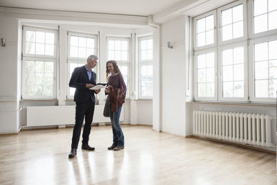 Real estate agent talking to client in empty apartment