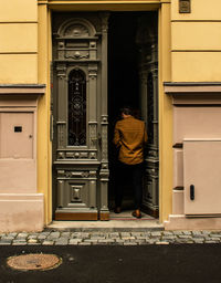 Rear view of man standing at entrance of building