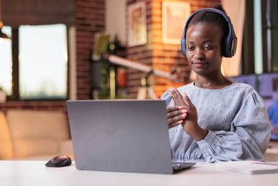 Young woman using laptop while sitting on table