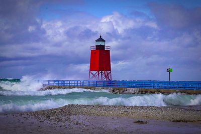 Lighthouse by sea against sky