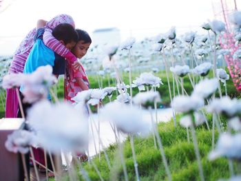 Siblings standing by flowers on field