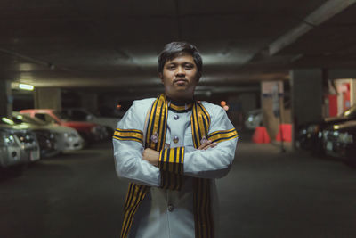 Portrait of young man with arms crossed standing at parking lot