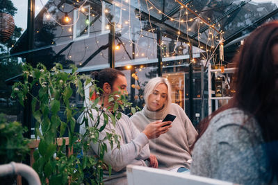 Multi-ethnic friends using mobile phone in glass cabin