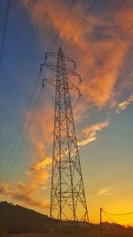 Low angle view of electricity pylon against sky during sunset