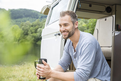 Smiling man sitting in a van at lakeside