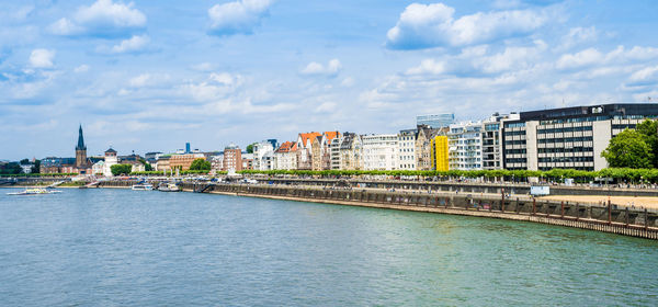 Bridge over river amidst buildings in city against sky