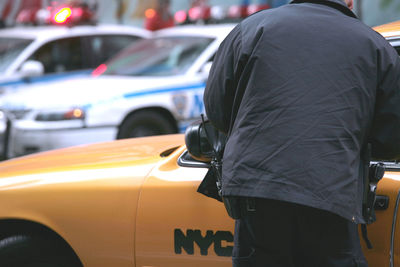 Policeman standing by yellow taxi in city