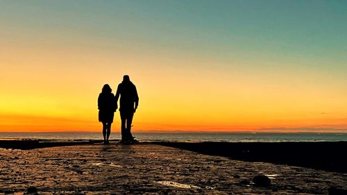 Silhouette people on beach during sunset