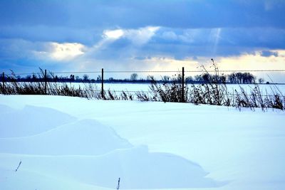 Snow covered landscape against cloudy sky