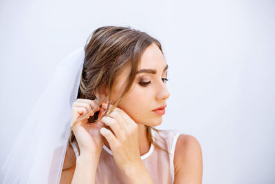 Beautiful young woman looking away against white background