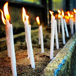 Close-up of burning candles in temple against building