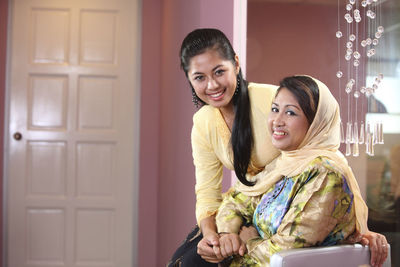 Portrait of mother and daughter smiling at home