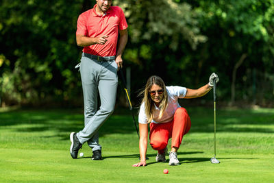 Couple playing golf, young woman reading green, getting ready to putt