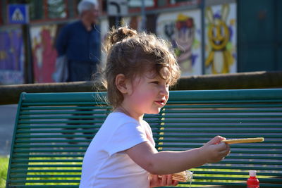 Side view of girl holding food while looking away outdoors