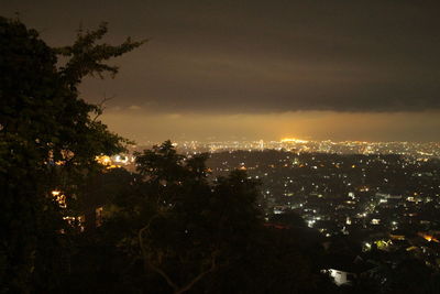 Illuminated cityscape against sky at night