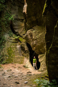 Rear view of woman standing on rock formation in cave