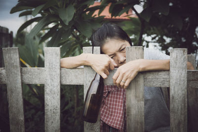 Man and woman by fence against trees