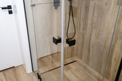 Enclosed glass shower door with matte black handles in a modern bathroom.