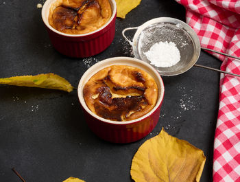 Cottage cheese dessert baked in portioned round ceramic plates on a wooden black table, top view