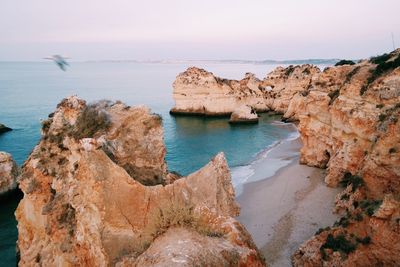 Rock formations on sea shore against sky