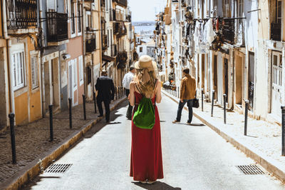 Rear view of woman standing amidst buildings in city