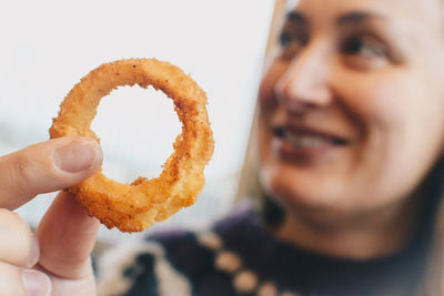 Woman holding onion ring while sitting at cafe