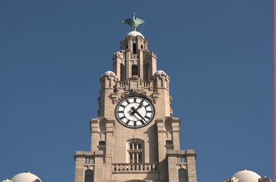 Low angle view of clock tower against blue sky