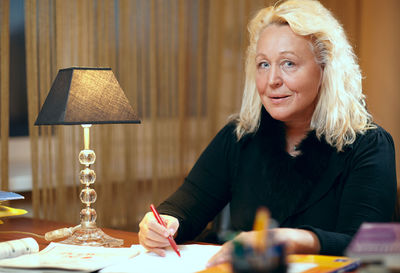 Portrait of senior teacher checking papers at table