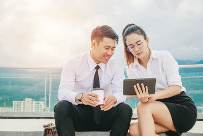 Businesswoman showing something on tablet to smiling colleague on balcony