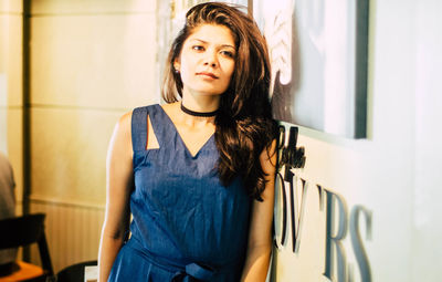 Portrait of beautiful young woman standing against wall