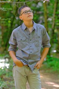 Mid adult man looking away while standing against trees