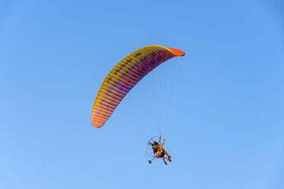 Low angle view of person paragliding against clear blue sky