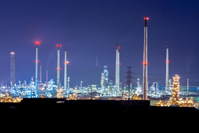 Illuminated factory against sky at night