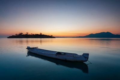 Boat moored on sea against sky during sunset