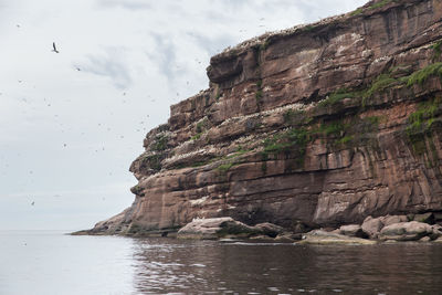 Rock formations by sea against sky