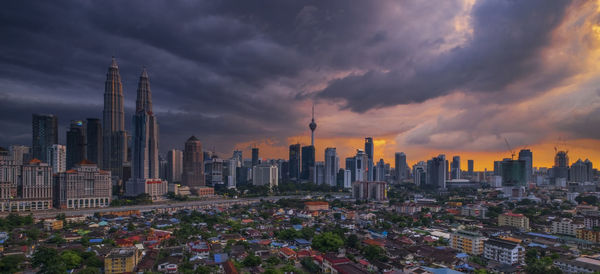 Aerial view of buildings in city against cloudy sky