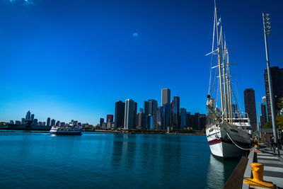 Boats moored in calm sea against clear blue sky