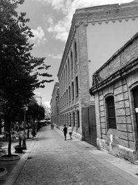 People walking on footpath amidst buildings in city