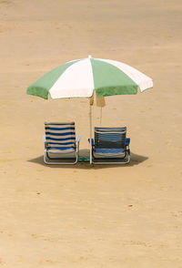 Deck chairs and parasol on sand at beach