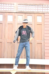 Full length portrait of man standing against brick wall