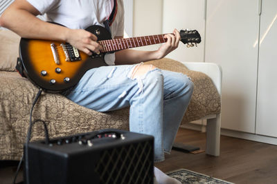 Midsection of man playing guitar