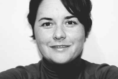 Close-up portrait of smiling young woman against white background