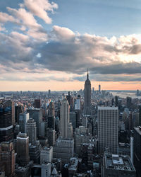 Aerial view of buildings in city against cloudy sky