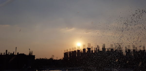 Silhouette buildings against sky during sunset