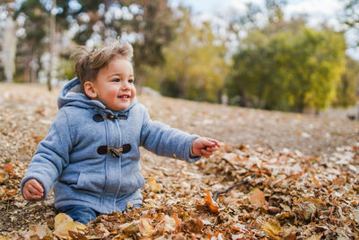 Boy playing with dry leaves during winter