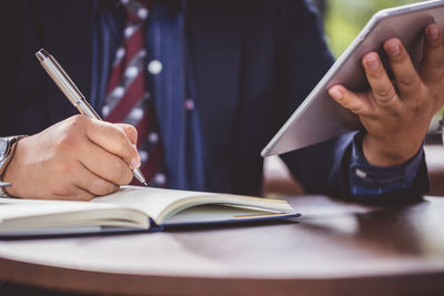 Midsection of man reading book on table