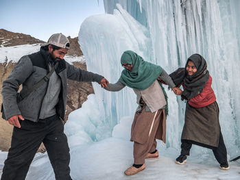 Friends standing on snow covered landscape during winter