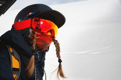 Portrait of a female snowboarder in a mask climbing to the top on a cable car at a ski resort