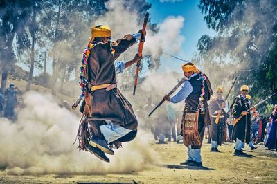 People wearing traditional clothing holding weapons