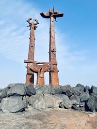 Low angle view of cross on rock against sky